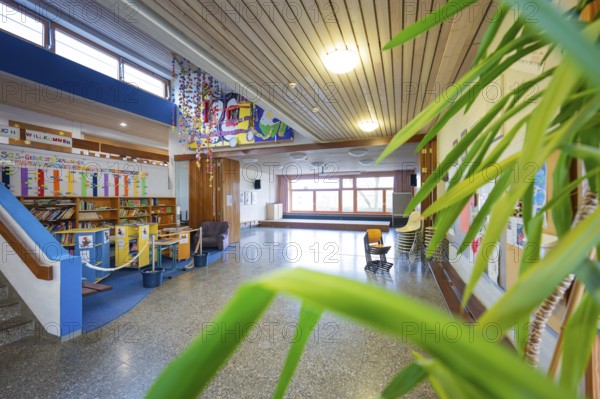 A bright school corridor with works of art, bookshelves and numerous plants in front of large windows, Schlehengäu Grund Schule Gechingen, Calw district, Germany