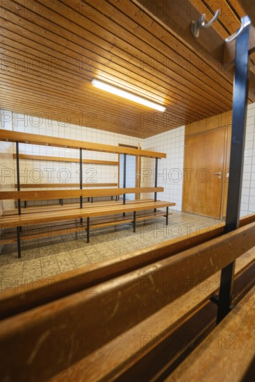 An empty changing room with wooden benches and simple lighting, Schlehengäu Grund Schule Gechingen, Calw district, Germany