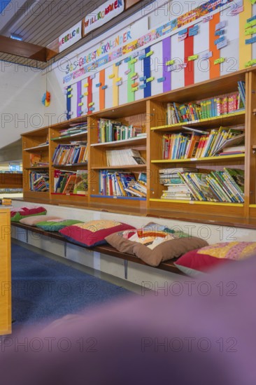 Educational area with well-stocked bookshelf and colorful seating, Schlehengäu Grund Schule Gechingen, Calw district, Germany