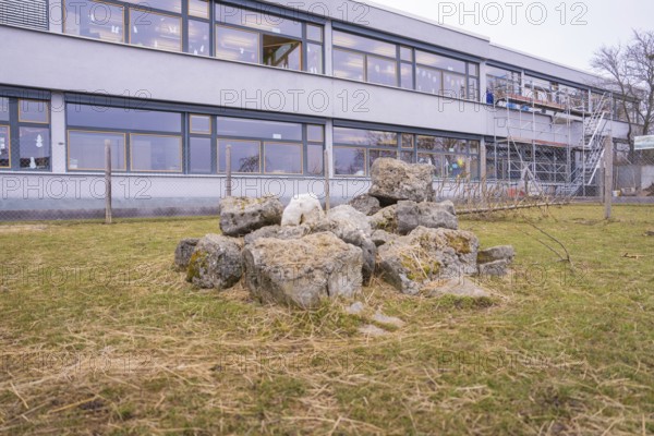 Piles of stones on the lawn in front of a school building with scaffolding in the background, Schlehengäu Grund Schule Gechingen, Calw district, Germany