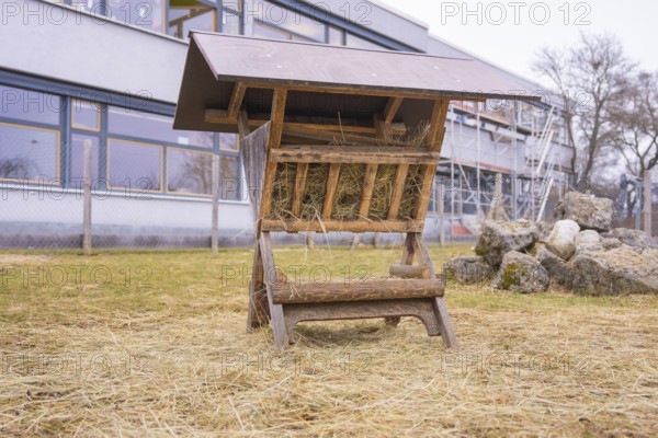 Wood hay rack on a hay covered meadow next to stones, Schlehengäu Grund Schule Gechingen, Calw district, Germany