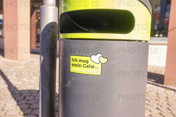 A trash can with city cleanliness sticker on a sunny day in public spaces, Calw, Calw district, Germany