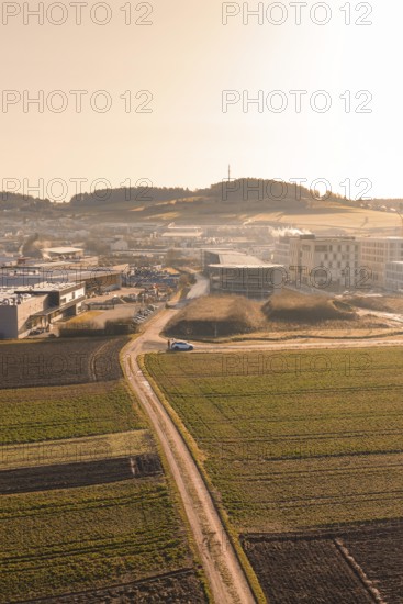 Rural road leads to large buildings in morning light over fields, new hospital at Calw health campus, Calw district, Germany