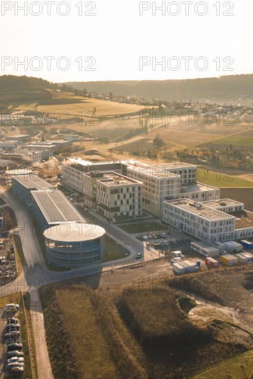 Modern buildings in an industrial area surrounded by fields at sunset, new hospital at Calw Health Campus, Calw district, Germany