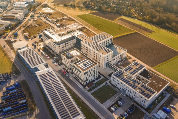 Modern buildings with solar panels surrounded by agricultural fields and industrial areas, new hospital at Calw Health Campus, Calw district, Germany