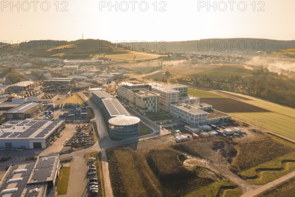 Aerial view of modern buildings in a vast rural area in the morning haze, new hospital at Calw Health Campus, Calw district, Germany