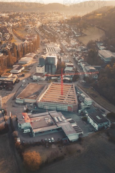 Aerial view of an urban building area with orange sky light and surrounding roads, Neubau Rewe, Aidlingen, Böblingen district, Germany