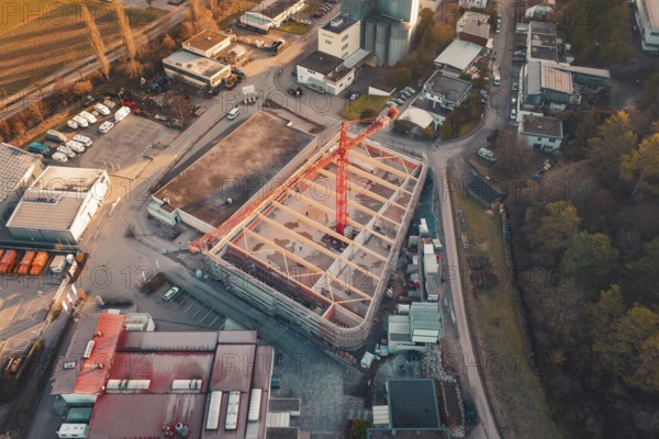 Aerial view of a construction site with crane in an urban area at sunset, surrounded by buildings and trees, Neubau Rewe, Aidlingen, Böblingen district, Germany