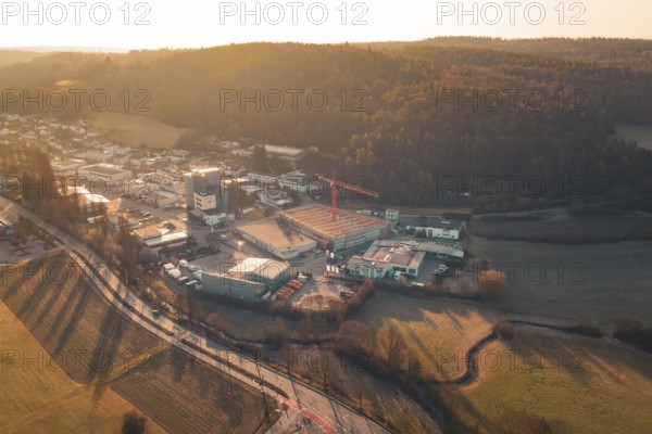 Landscape scene at sunset with road, urban area and hills in the background, Neubau Rewe, Aidlingen, Böblingen district, Germany