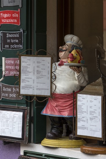 Cooking figure with fish in front of a restaurant, Burano, Veneto, Italy