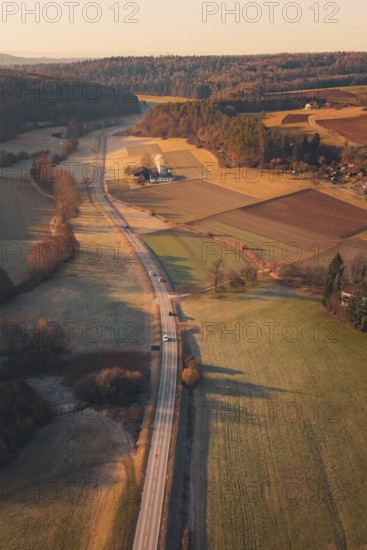 A country road winding through fields and hills in warm sunlight, Aidlingen, Böblingen District, Germany