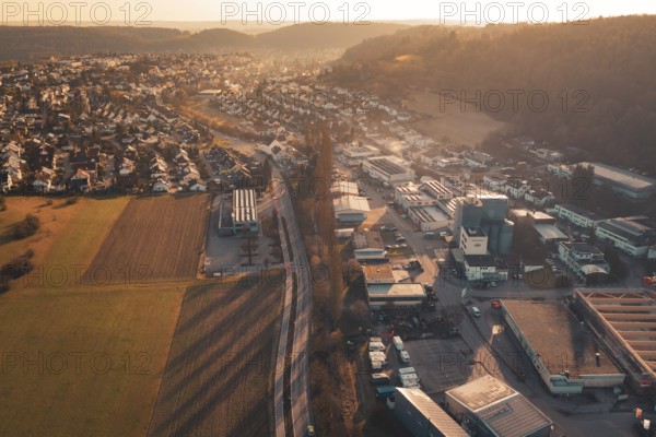 Commercial and residential areas blending with fields and hills under sunset glow, Aidlingen, Böblingen District, Germany