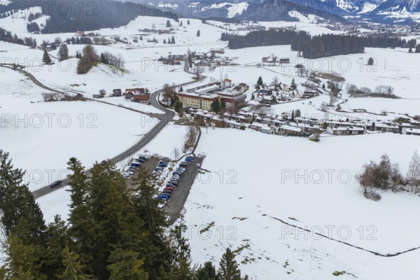 Snow-covered winter landscape with a village, forest trail and fields in the foreground, specialist clinic for psychosomatics and psychotherapy, Hochgrat Clinic, Stiefenhofen, Bavaria, Germany