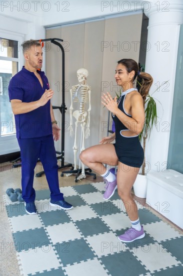 Physical therapist guiding female patient through a high knees exercise for medical recovery and sports rehabilitation in a modern clinic with a skeletal model
