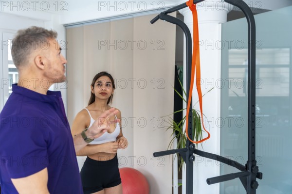 Physiotherapist explaining exercise instructions to a female patient. Providing guidance and support for muscle strengthening during a recovery therapy session in a professional clinic or gym setting