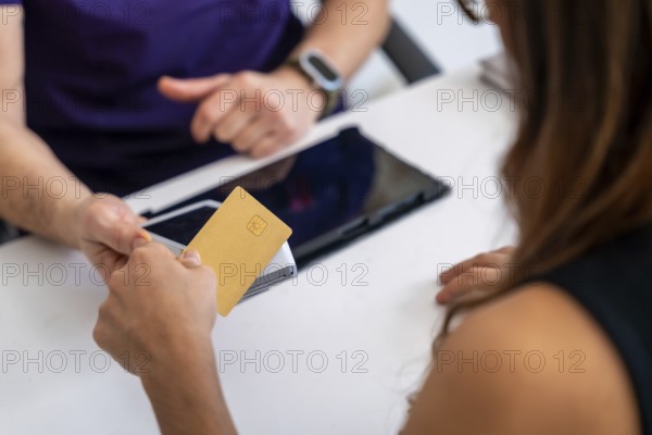 Patient paying medical bill with a credit card at a clinic reception, completing a healthcare transaction after a physical therapy appointment using modern technology