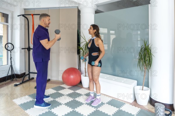 Physiotherapist showing a woman how to perform exercises with dumbbells, focusing on strength training and physical recovery, improving health and wellness