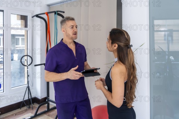 Male physiotherapist discussing rehabilitation and wellness strategies with a young female patient in a medical office, focusing on recovery and professional consultation