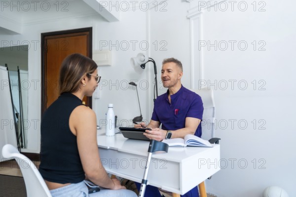 Healthcare professional wearing a uniform discussing medical recovery and sports osteopathy with a young female patient in a clinic office, developing a customized physiotherapy treatment