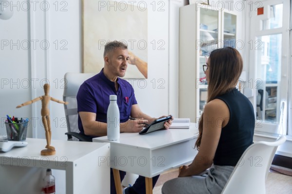 Medical professional wearing scrubs discussing therapy options and recovery plans with a female patient during a consultation in a modern office, focusing on health and rehabilitation strategies