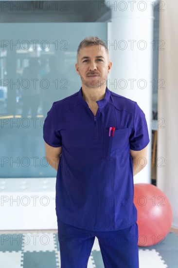 Professional physiotherapist wearing a purple scrub uniform is standing confidently in a modern rehabilitation clinic, ready to provide therapy and support for sports injuries and physical recovery