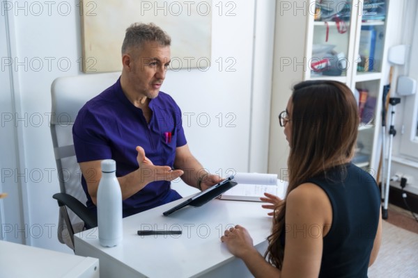 Healthcare professional explaining treatment options to a young woman during a consultation in a clinic, focusing on sports osteopathy and medical recovery to improve wellbeing