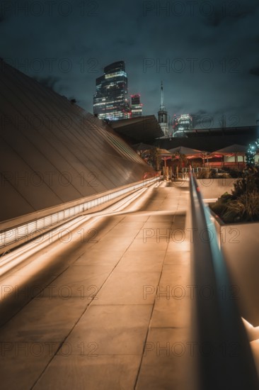 Illuminated modern architecture path leading to London skyline at night, London, United Kingdom