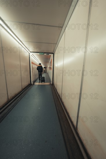 Long airport aisle with a traveller pulling a trolley bag, London, United Kingdom