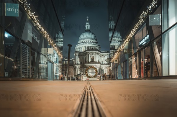 View of an illuminated cathedral between two modern buildings at night, London, Great Britain