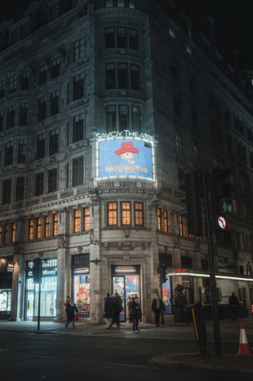 Illuminated theatre building at night with advertisement for a performance, London, Great Britain
