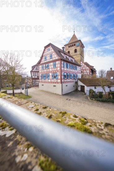 View of half-timbered houses and church tower with cobblestones and blue sky, Ötisheim, Enzkreis, Germany