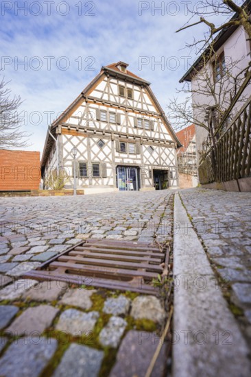 Half-timbered house with cobblestone street and wooden fence in a historic setting, Ötisheim, Enzkreis, Germany