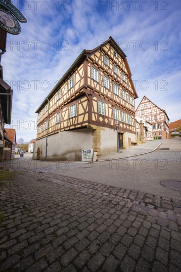 Two large half-timbered houses with red and white details on a busy street corner, Ötisheim, Enzkreis, Germany