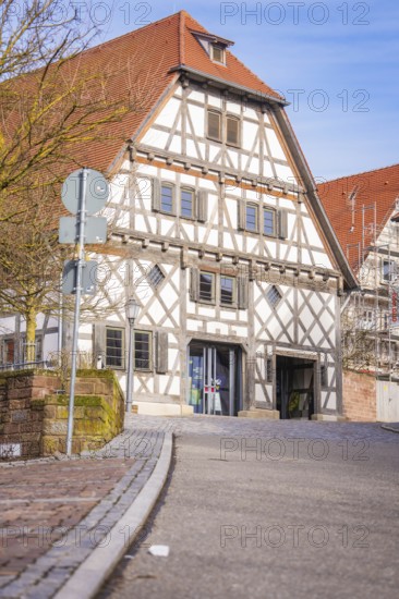 Timbered house with red roof and road signs against a blue sky, Ötisheim, Enzkreis, Germany