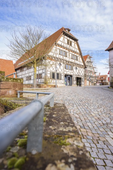 Traditional half-timbered house on cobblestone road under blue sky, Ötisheim, Enzkreis, Germany