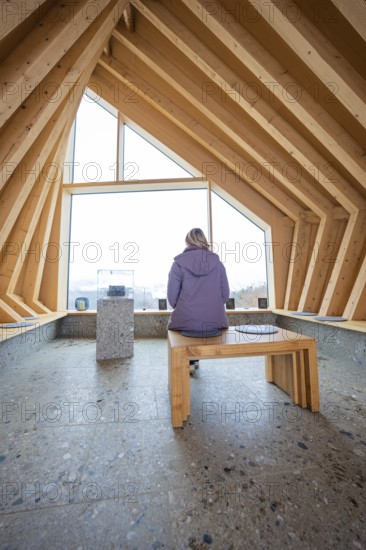 Person sitting on a bench in a modern wooden room with window view, Sinnraum, Oberreute, Allgäu, Bavaria, Germany