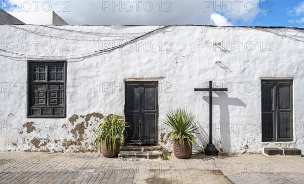 Typical white house with wooden doors and windows in an alley with volcanic crater at the back, Teguise, Lanzarote, Canary Islands, Spain