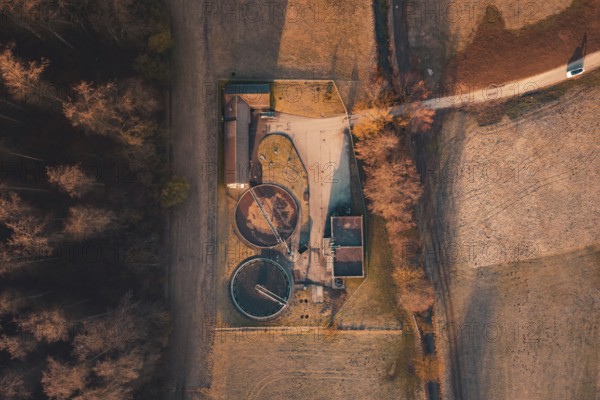 Sewage treatment plant with round basin and buildings from above, surrounded by fields and forest in autumn light, Gechingen, Calw district, Germany