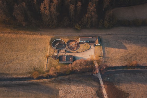 Sewage treatment plant with round basins and buildings in the midst of a wide field landscape with autumn colors, Gechingen, Calw district, Germany