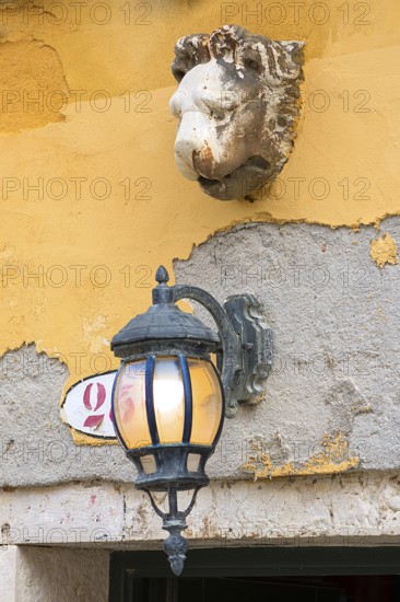 Sculpture of a lion's head and lantern above an entrance, Venice, Veneto, Italy