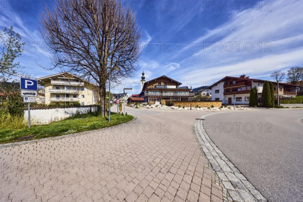 Alpine buildings, road, curve, church tower, parking lot, Alpenliebe Design Hotel, bare winter trees, blue sky, cirrus clouds, cirrostratus clouds, intersection between Fritz-Gastager-Straße and Reichenhaller Straße, Inzell, Traunstein district, Bavaria, Germany