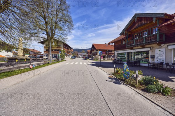 Houses, general architecture, alpine buildings, residential buildings and commercial buildings, street, wooden fence, pedestrian crossing with zebra crossing and traffic sign, trees with spring leaves, blue sky, cirrus clouds, cirrostratus clouds, Traunsteiner Straße, Inzell, Traunstein district, Bavaria, Germany