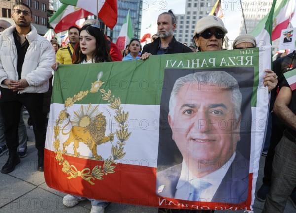 Iranians demonstrate with a poster of Prince Reza Pahlavi on the day of the US and Israeli attack on Iran, Berlin, 28.02.2026. People wave flags of the Iranian monarchy, German, Israeli and US flags, Berlin, Berlin, Germany