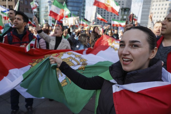 Iranians demonstrate with a large imperial Iranian flag on the day of the US and Israeli attack on Iran in Berlin, 28.02.2026. People cheer the rumor that Obermullah Khamenei died in the attack, Berlin, Berlin, Germany
