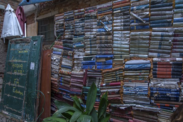 Stacked books on a wall after flood damage in a bookstore, Venice, Veneto, Italy
