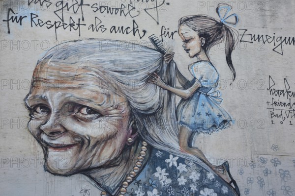 Mural from Herakut 2015, old woman with girl hairdressing her long hair, cosmetics, saying, face, head, house facade, symbol of respect, appreciation, relationship, interaction, giving, and taking, Bad Vilbel, Wetterau, Hesse, Germany