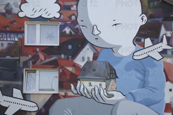 Mural by CASE MacAclaim and Millo, street art, graffiti, child carrying house in hands, illustration, comic, airplane, carrying, Andreas von Chrzanowski, Francesco Camillo Giorgino, Bad Vilbel, Wetterau, Hesse, Germany