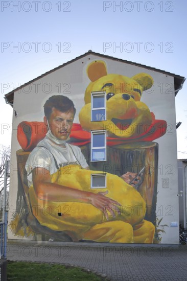 Mural Waldsterben by CASE MaClaim 2024, man with yellow plush toy, bear figure, street art, photorealistic graffiti, house facade, symbol, Bad Vilbel, Wetterau, Hesse, Germany