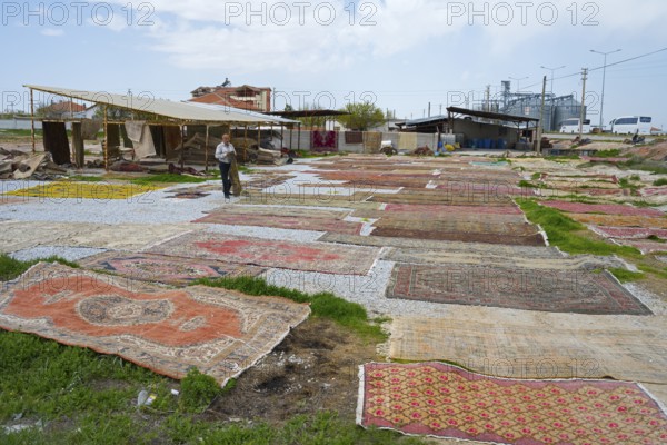 Open-air market with a variety of carpets spread across grasses and pebbles, Aksaray province, Turkey