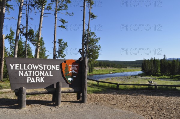 Yellowstone National Park entrance sign with trees and a river in the background, Yellowstone National Park, Wyoming, USA